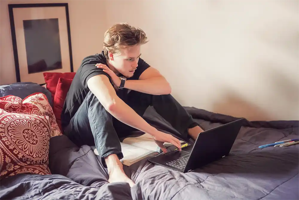 Male college student studying on the bed alone
