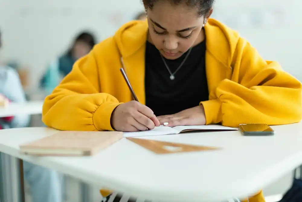 Young teen girl works at a desk in a classroom